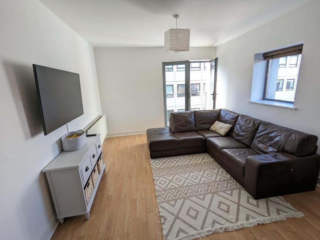 sala de estar con sofá de cuero y TV de pantalla plana en Best Location in Belfast! Free parking, en Belfast