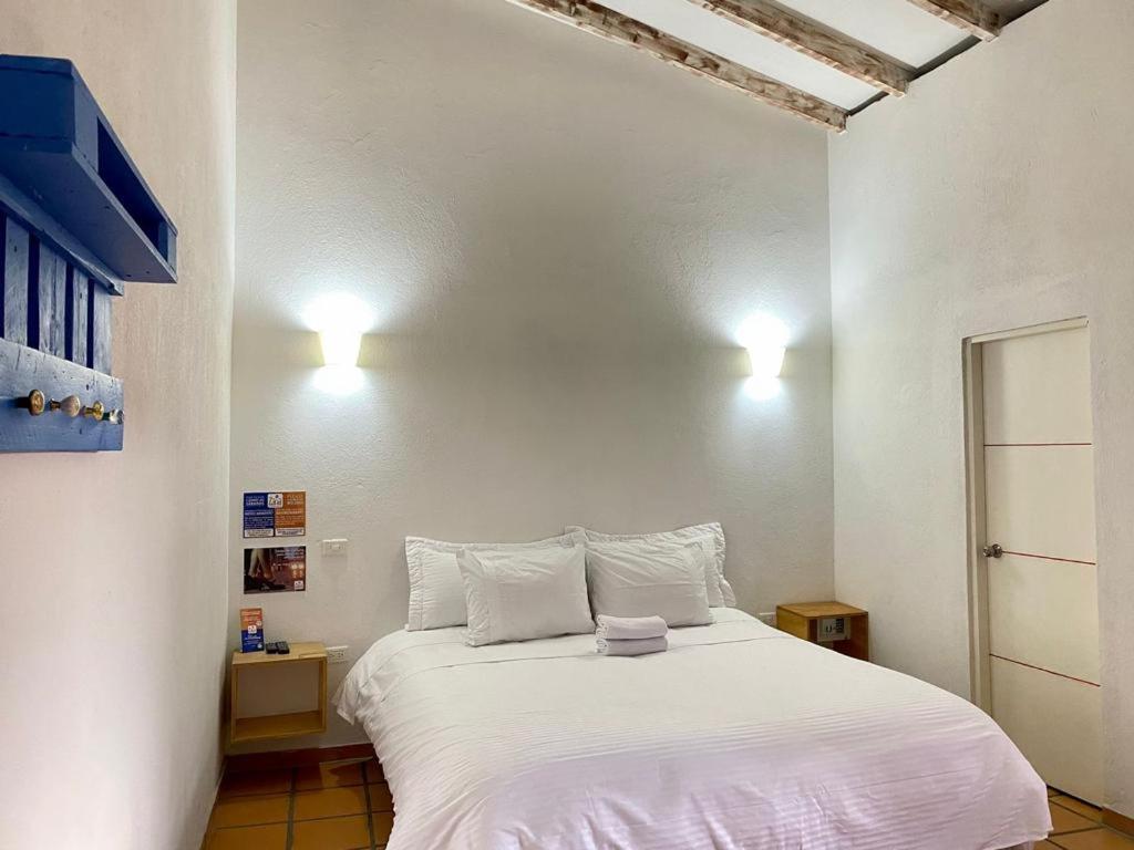 a bedroom with a large white bed with two pillows at Zana Hotel Boutique in Bogotá