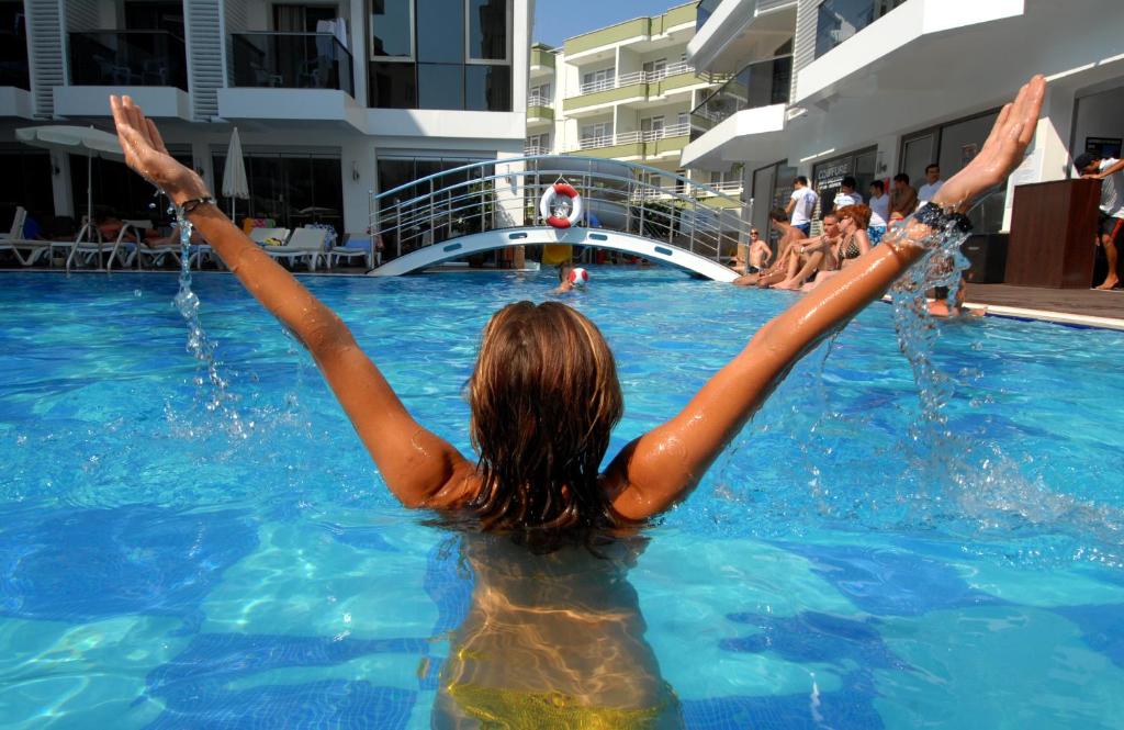 una mujer en una piscina con sus brazos en el agua en Oba Star Hotel - Ultra All Inclusive, en Alanya