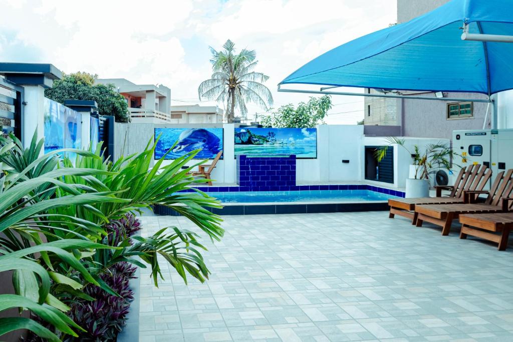 un patio con una sombrilla azul y algunas plantas en Richie's Appartments en Accra