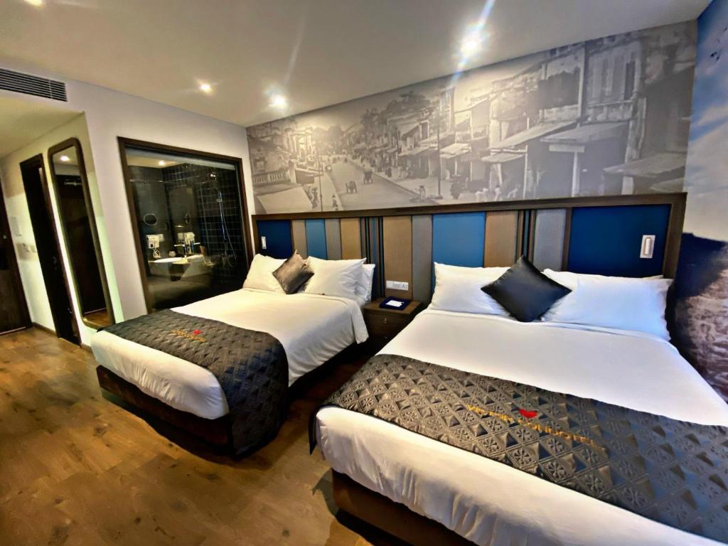 a hotel room with two beds and a mural at Apec Mandala Chambay Mui Ne in Ấp Nhơn Ðúc