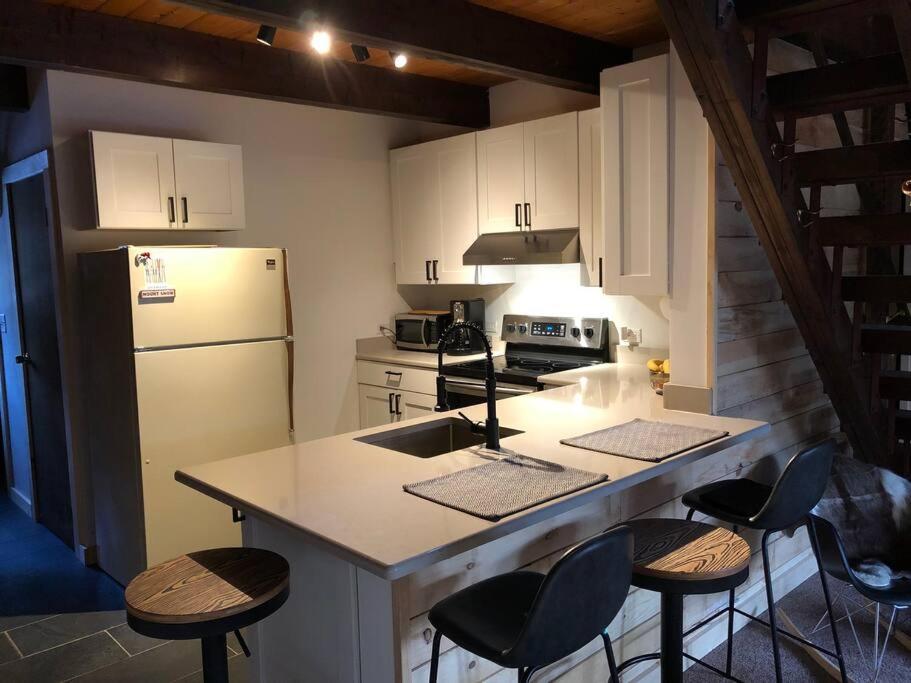 a kitchen with a white refrigerator and a counter with stools at Mount Snow A Frame with Jacuzzi in Dover