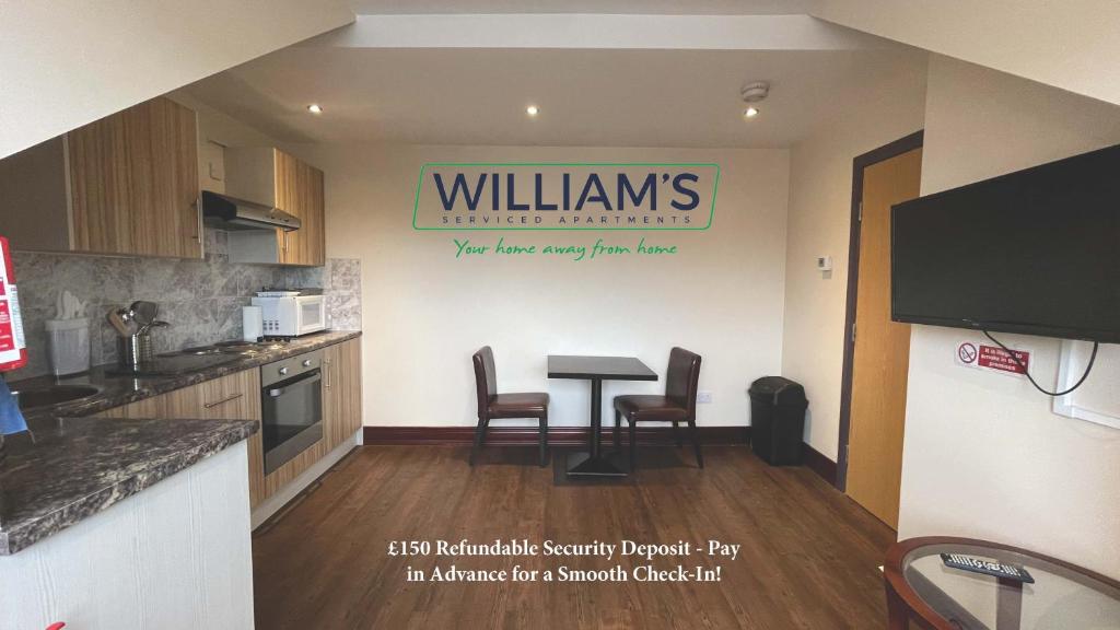 a kitchen with a table and chairs and a sign on the wall at William's Hillsborough Apartments in Sheffield