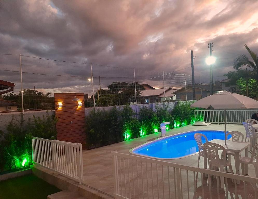 a backyard with a swimming pool with green lights at Recanto Munik in Palhoça