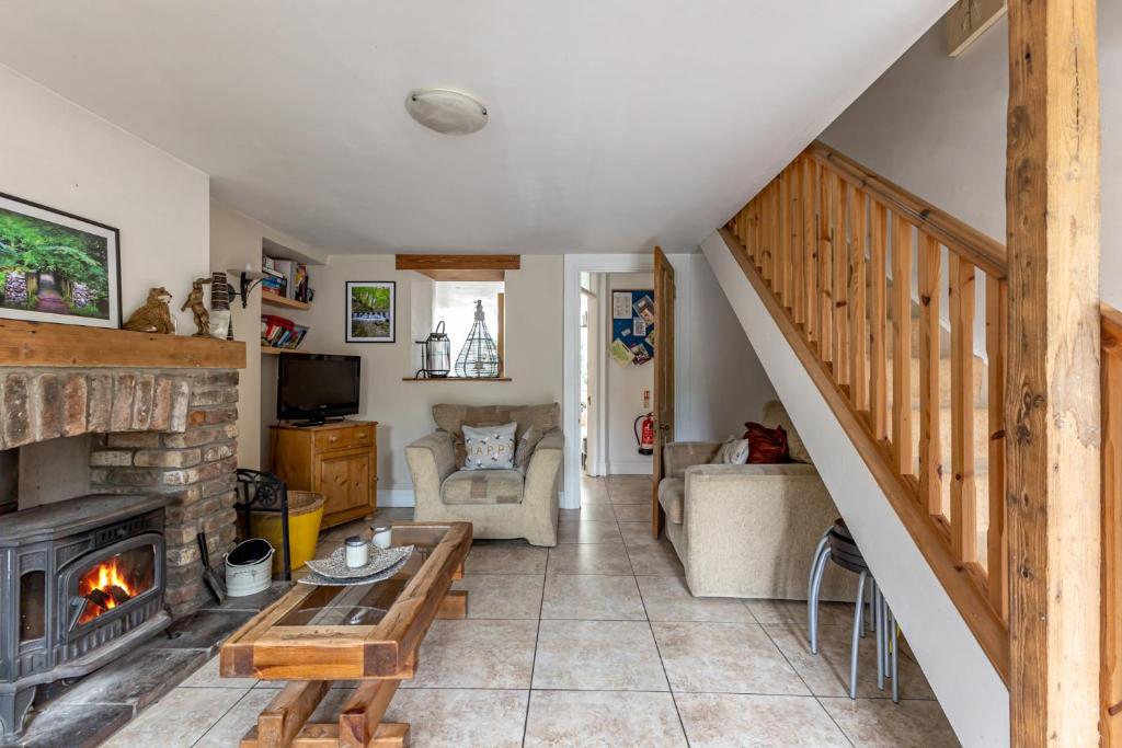 a living room with a staircase and a fireplace at Priest Bridge Cottage in Bryansford