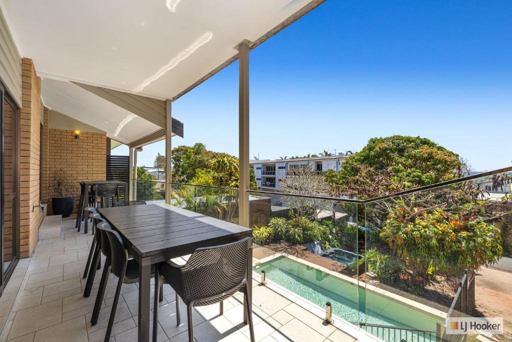 a balcony with a table and chairs and a swimming pool at Kingscliff Ocean Vista in Kingscliff
