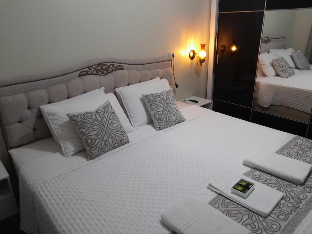 1 dormitorio con 1 cama blanca grande y espejo en Hospedom Mazzoca 01, WC compartilhado, en Itapema
