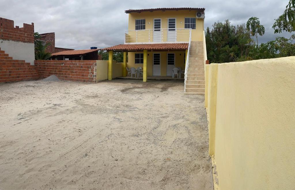 a yellow house with a dirt yard in front of it at Flatsuico in Fortim