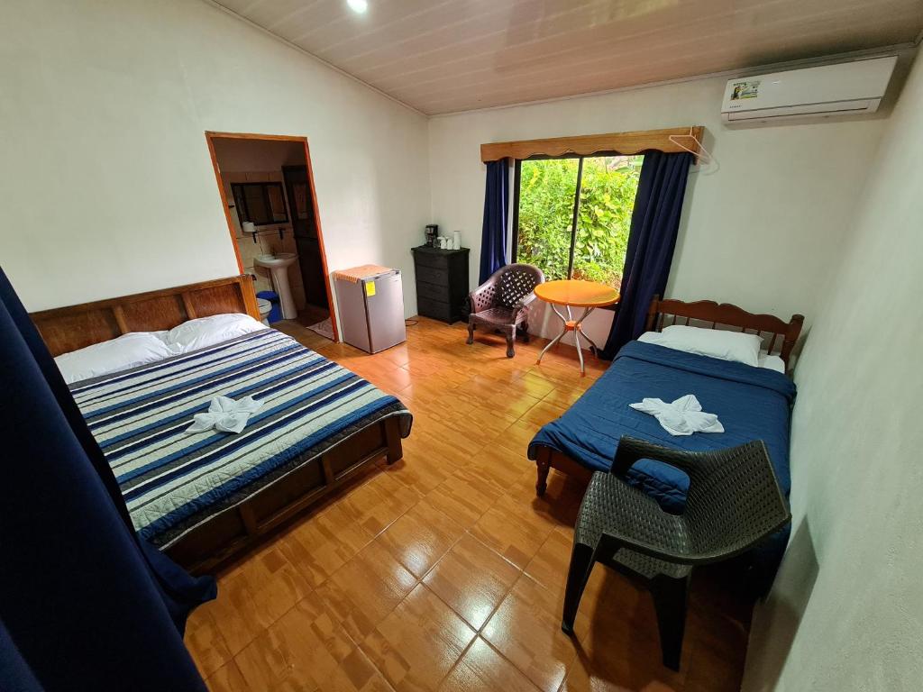 德雷克的住宿－Osa Corcovado Lodge，一间卧室配有两张床、一张桌子和一把椅子