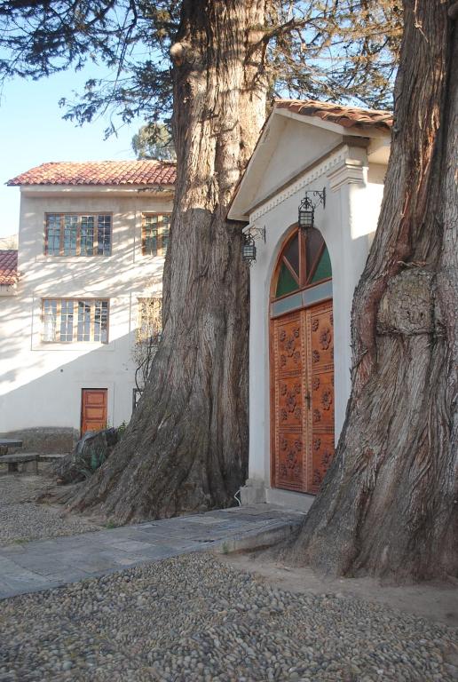 uma casa com uma grande árvore ao lado de uma porta em Hostal La Chacarilla em Copacabana