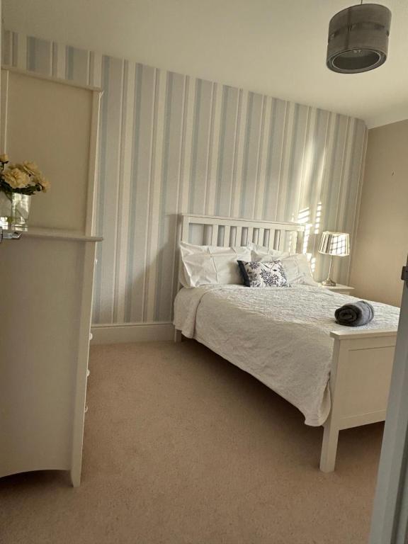 a bedroom with a white bed with a cat laying on it at LN Host in Hardingstone