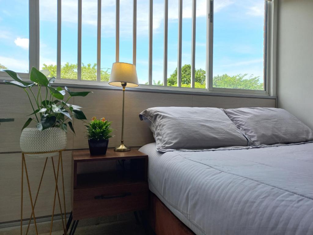 um quarto com uma cama e uma mesa com um candeeiro em Moderna y confortable habitación em Floridablanca