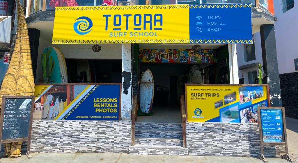 una scuola di surf con dei cartelli di fronte di Totora Surf Hostel a Huanchaco