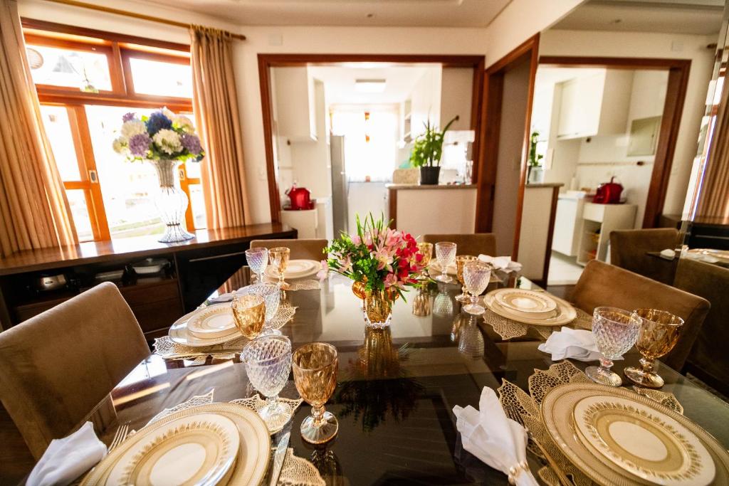 a dining room table with plates and flowers on it at Luxuoso duplex no Capivari in Campos do Jordão