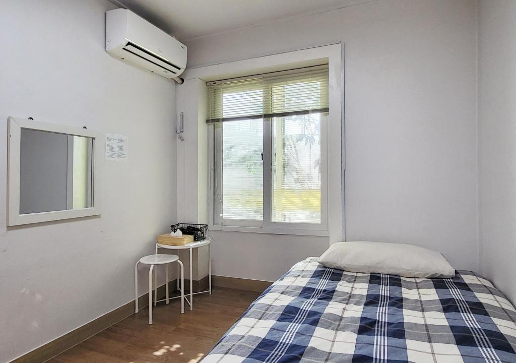 een kleine slaapkamer met een bed en een raam bij Hongdae Cheese Guesthouse in Seoul