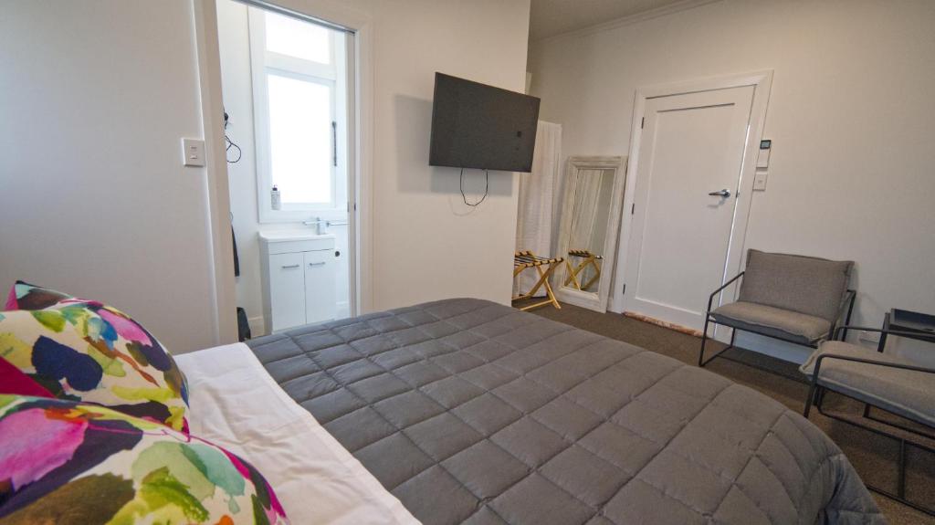 1 dormitorio con 1 cama, 1 silla y TV en Cosy on Stirling en Oamaru