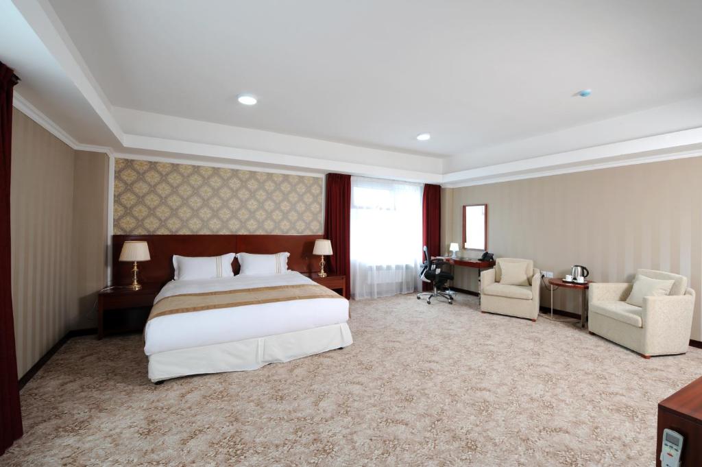 a hotel room with a bed and two chairs at Alpha Hotel Ulaanbaatar in Ulaanbaatar