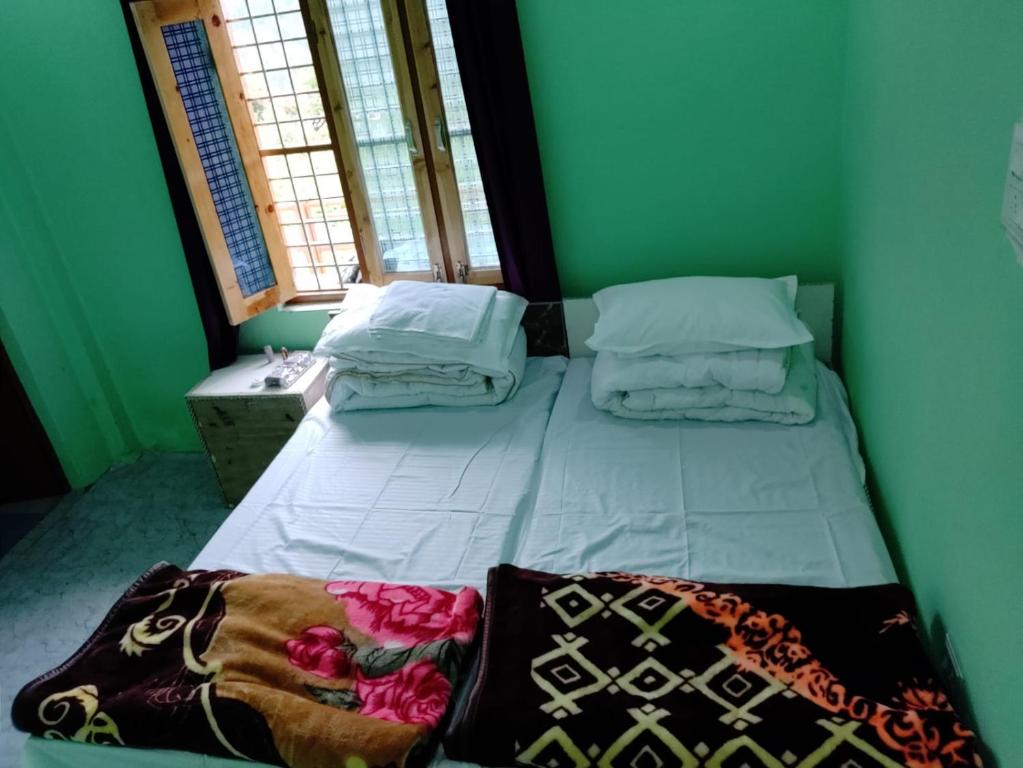 a bed in a room with two windows at Shivashram in Joshīmath
