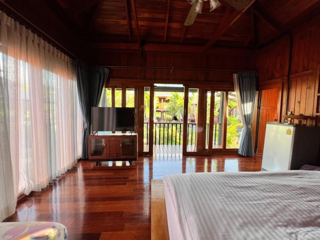 a bedroom with a bed and a flat screen tv at Bann Rai I Na in Phrae
