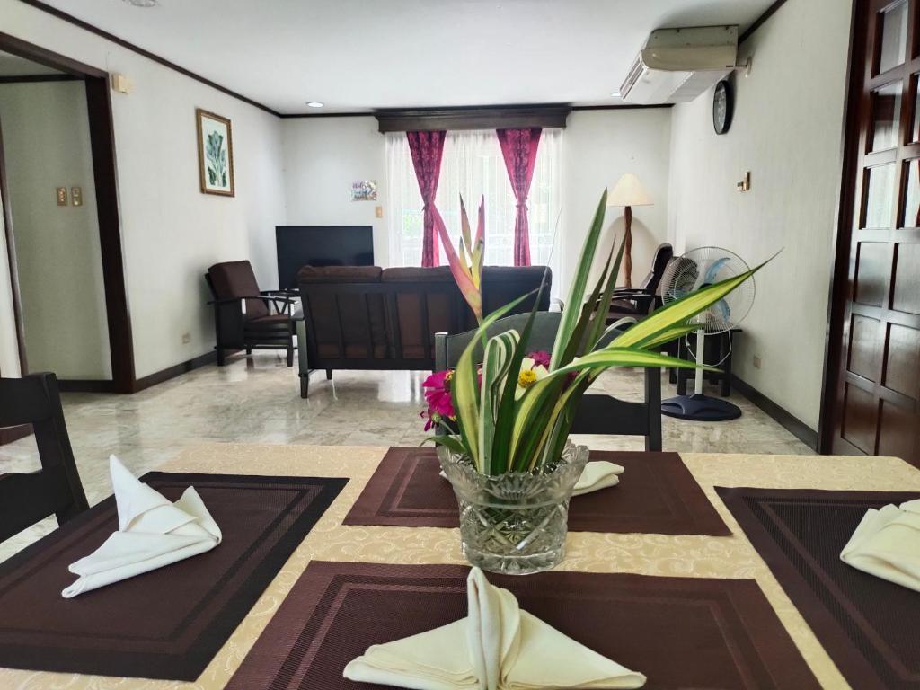 Tropical Paradise Retirement Village Inc في Sawat: غرفة معيشة مع طاولة مع إناء من الزهور