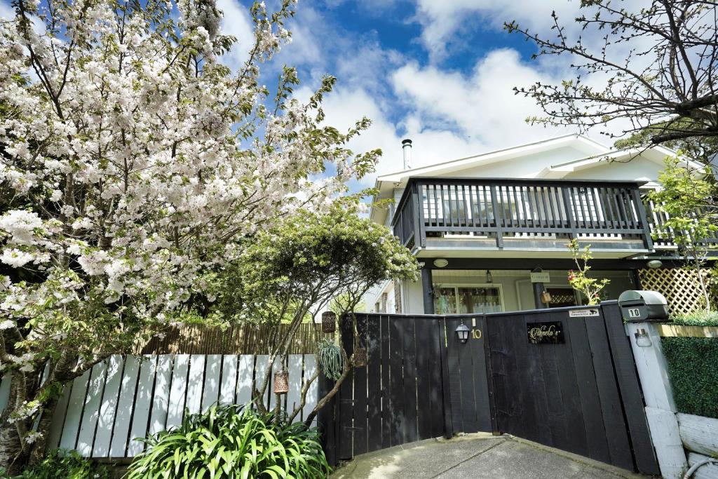 a house with a black fence and a flowering tree at Entire ground floor with full-privacy and family-friendly popular to ferry catchers in Wellington