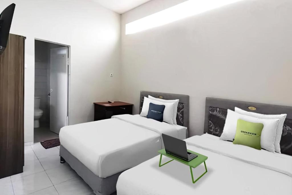 a bedroom with two beds and a laptop on a table at Kozy 15 Guesthouse in Surabaya