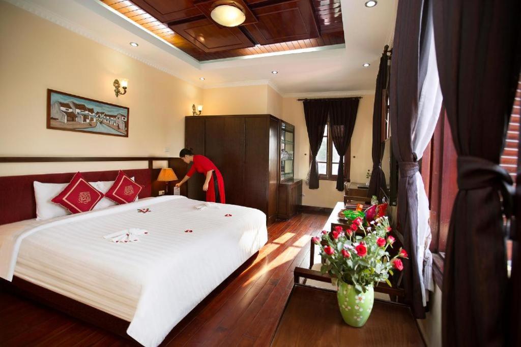 ein Schlafzimmer mit einem großen weißen Bett und Blumen in der Unterkunft Hanoi Posh Boutique Hotel in Hanoi