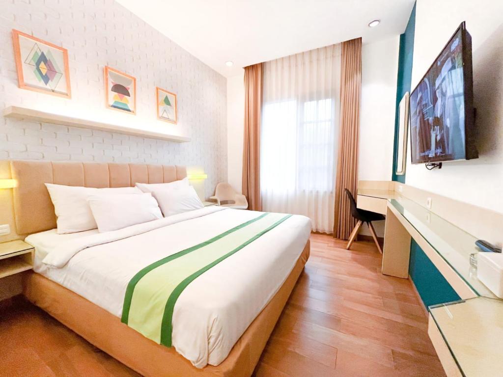 a hotel room with a bed and a flat screen tv at Hotel Wisata Niaga Campus in Purwokerto