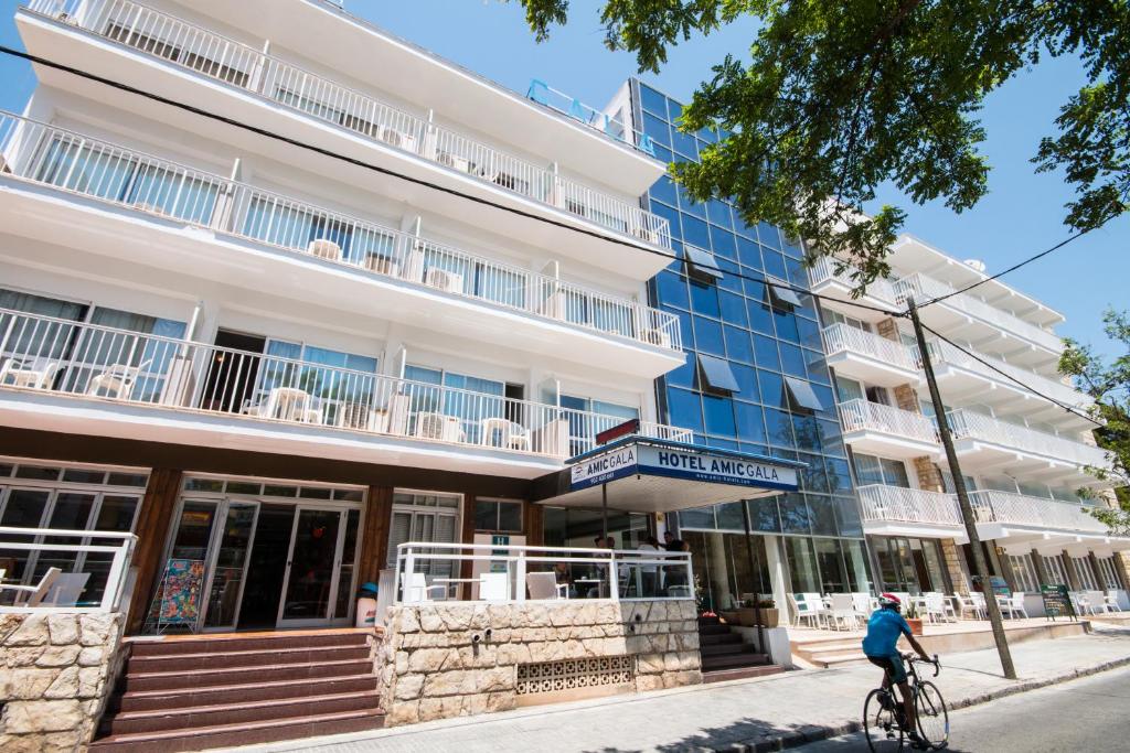 uma pessoa a andar de bicicleta em frente a um edifício em Hotel Amic Gala em Can Pastilla