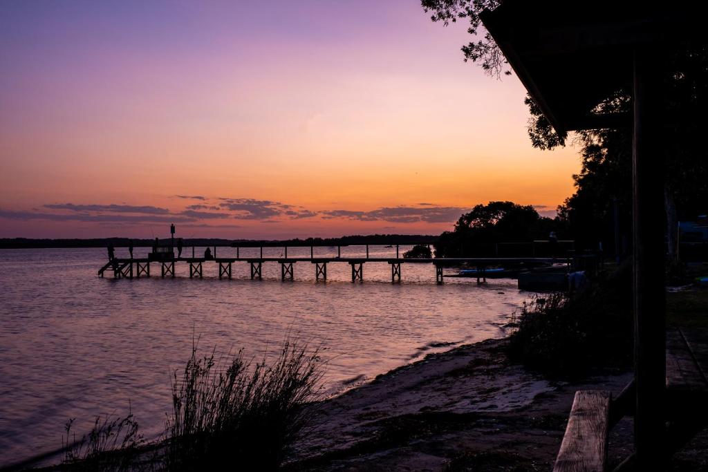 Lemon Tree Passage的住宿－Koala Shores Holiday Park，水面上的码头,背景是日落