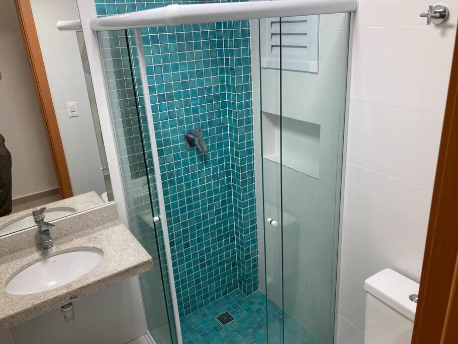 La salle de bains est pourvue d'une douche en verre et d'un lavabo. dans l'établissement Belíssimo apartamento com vista praia, à Praia Grande
