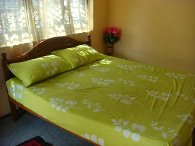 Una cama con una colcha verde con flores blancas. en Randi Homestay en Negombo