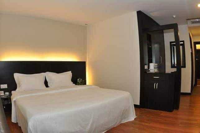 1 dormitorio con cama blanca y armario negro en H-5 INN, en Bintulu