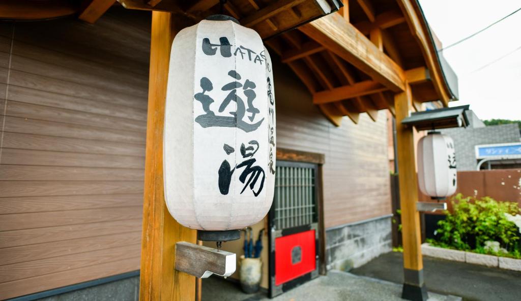 a surfboard with asian writing on the side of a building at Kamegawa Onsen HATAGO Yuyu in Beppu