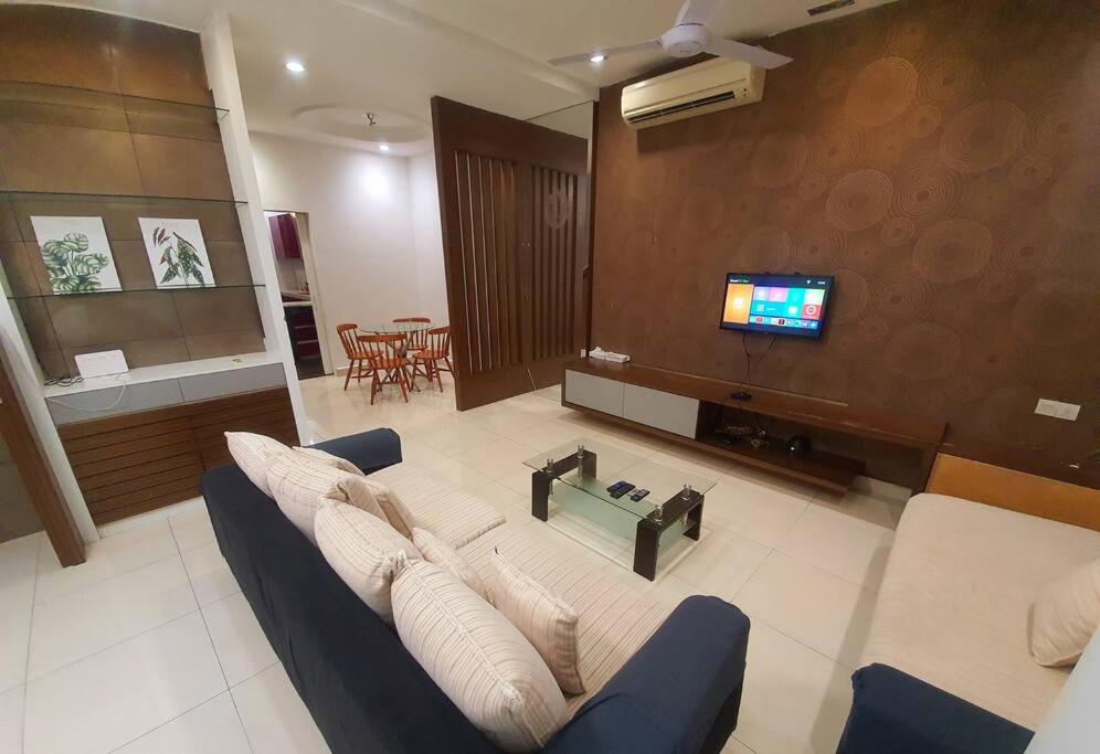uma sala de estar com um sofá e uma televisão em CozyHouse 4ROOM 4BATH ROOM 8PAX@Near BM Icon city em Bukit Mertajam