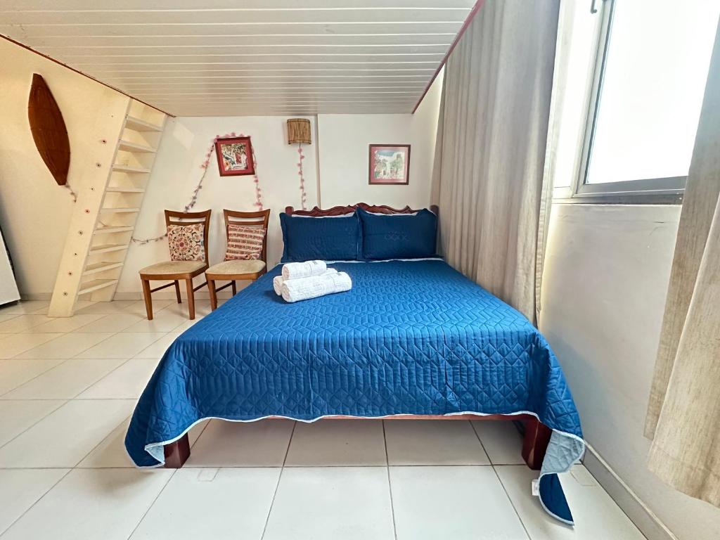 a bedroom with a blue bed and two chairs at STUDIO COPA IPA ARPOADOR Ap 304 in Rio de Janeiro