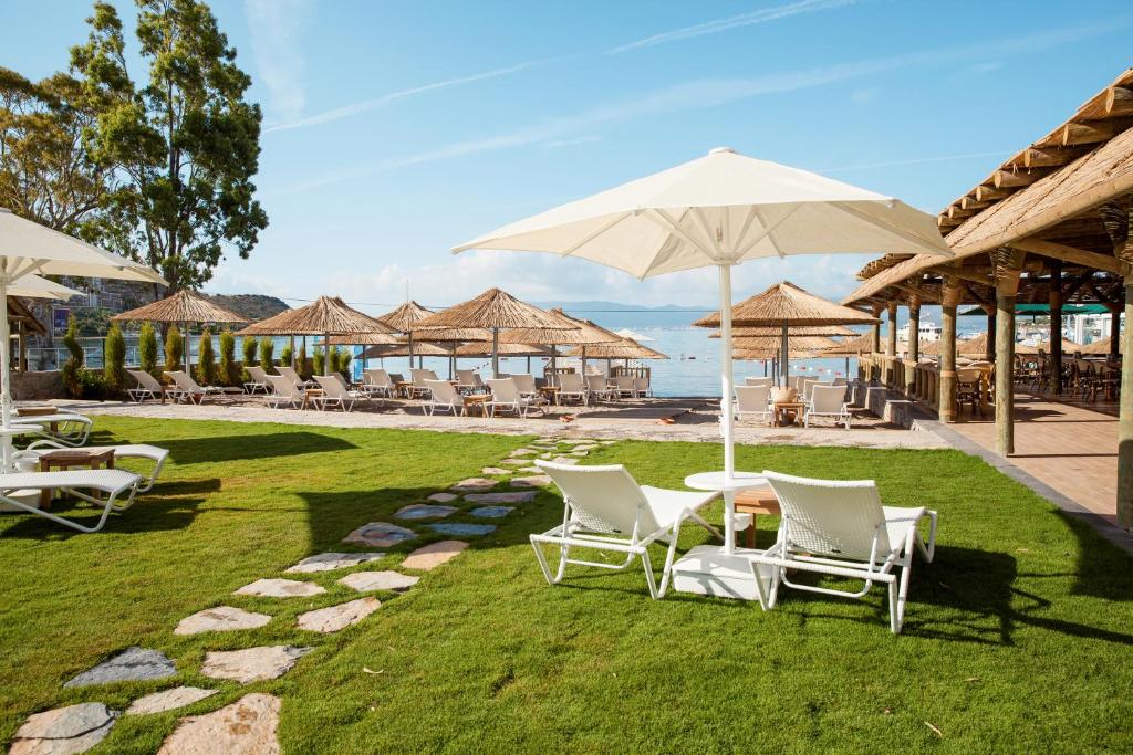 a group of chairs and tables with umbrellas on the grass at Bellazure Hotel in Akyarlar