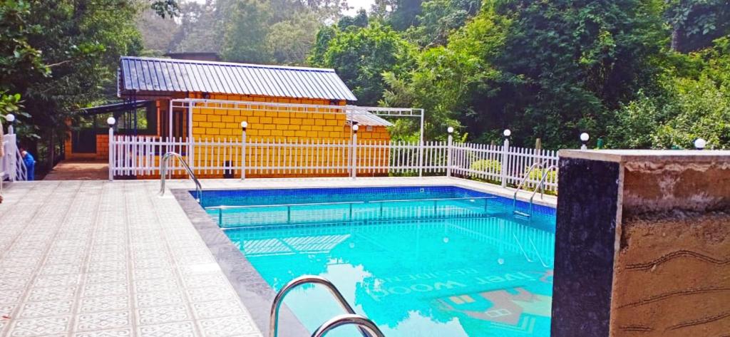 a swimming pool with a building in the background at STAYMAKER River Wood Residency in Dandeli