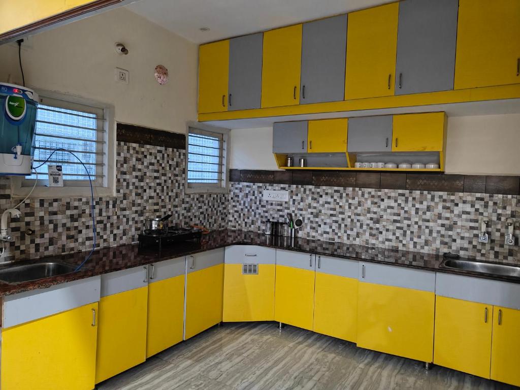 uma cozinha com armários amarelos e um lavatório em 2Bhk holiday home em Mysore