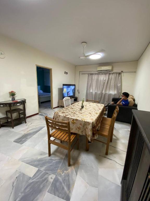 a living room with a table and a person laying on a couch at PakYa Homestay in Kampong Padang Jawa