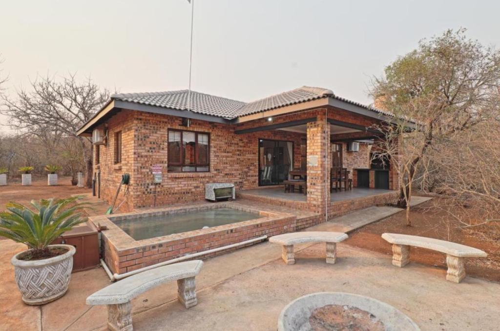 a brick house with a pool in the backyard at Adventure Bush Manor in Marloth Park