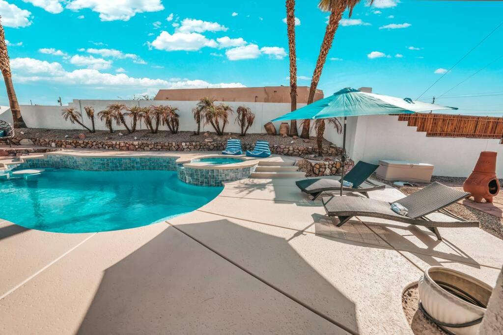 a swimming pool with chairs and an umbrella at BOHO House - Pool, Spa, Boat Parking, Central in Lake Havasu City