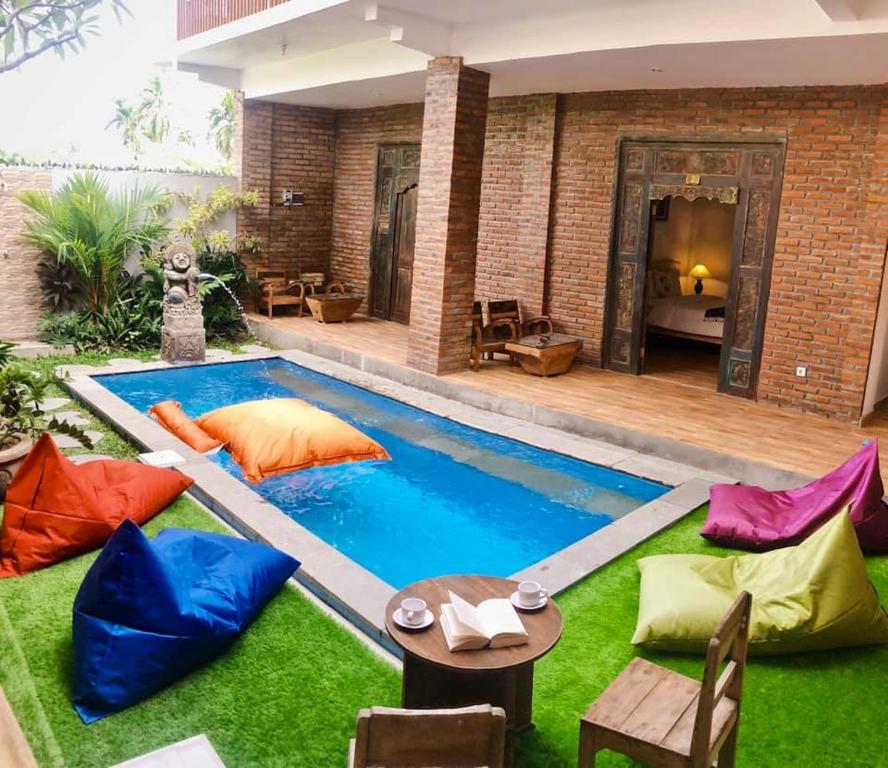 a backyard with a pool with colorful pillows and a table at Pondok Kita in Canggu