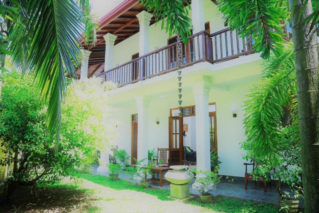 uma casa branca com varanda e árvores em Residence Chanty em Hikkaduwa