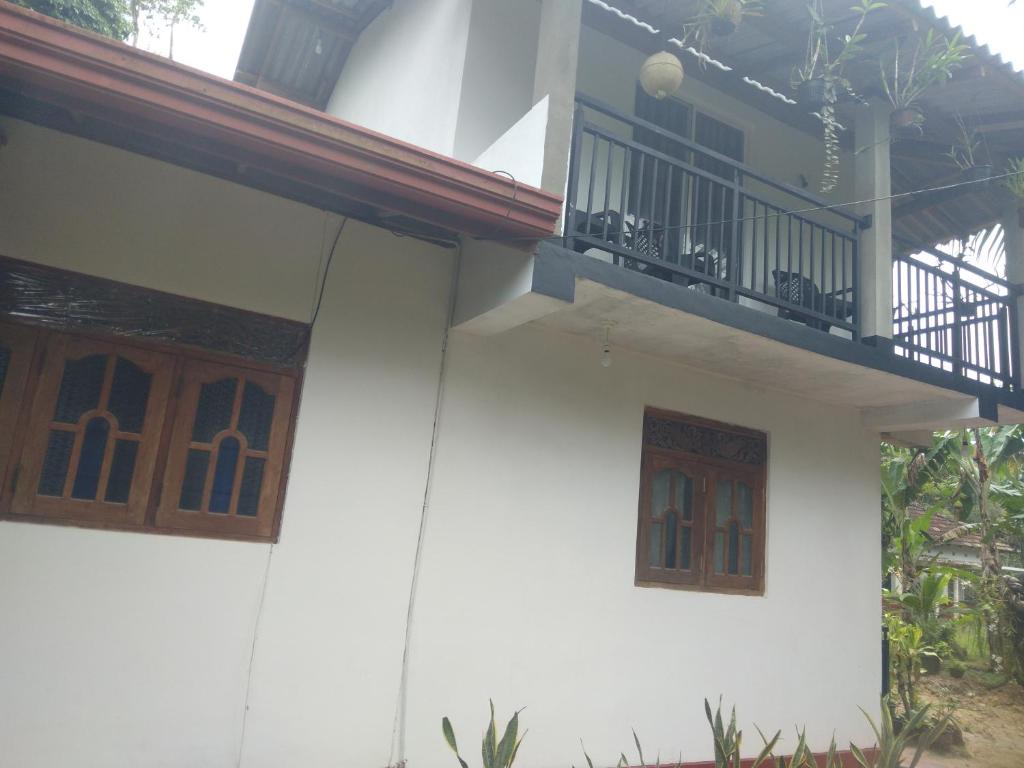 a white house with a balcony and a porch at Olive Launch in Weligama