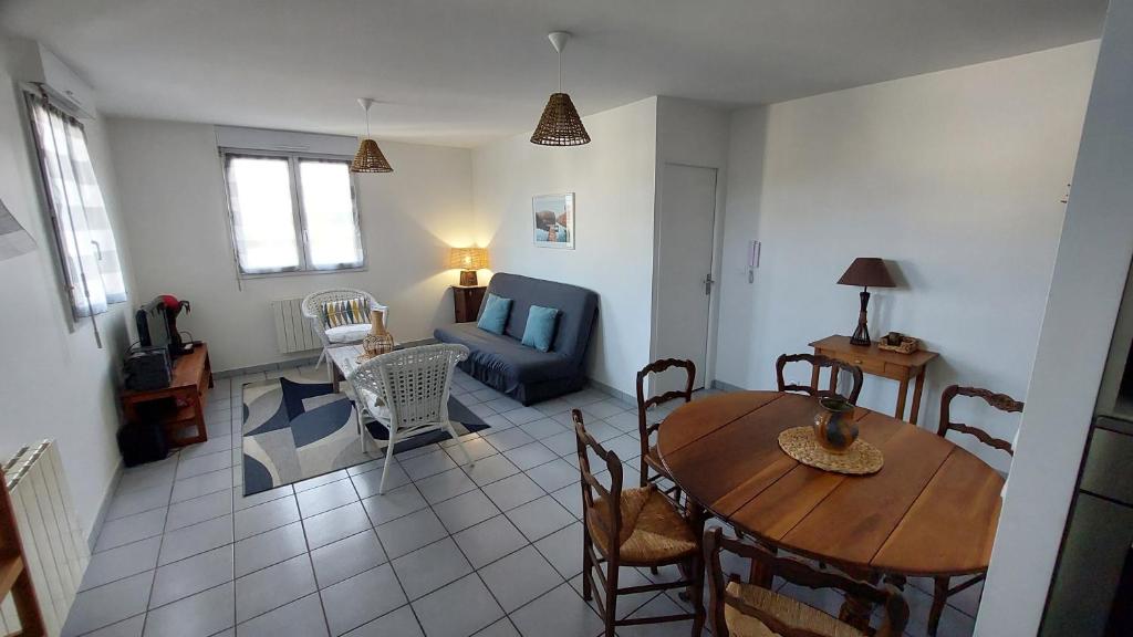 uma sala de estar com uma mesa e um sofá em Bel appartement au calme em Sainte-Geneviève-des-Bois