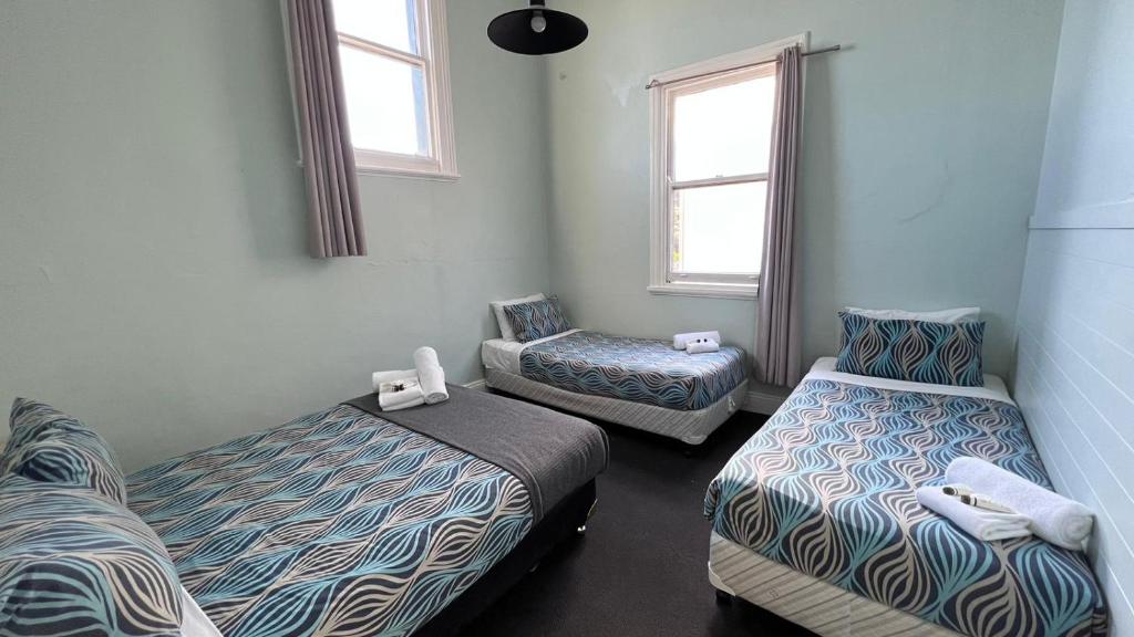 Zimmer mit 2 Betten und 2 Stühlen in der Unterkunft Beachside Budget Rooms in Kiama
