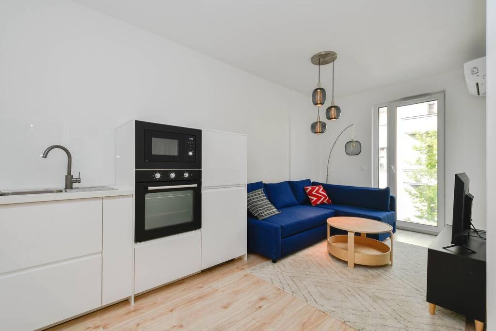 un salon avec un canapé bleu et une cuisine dans l'établissement New modern apartment in city center, à Bratislava