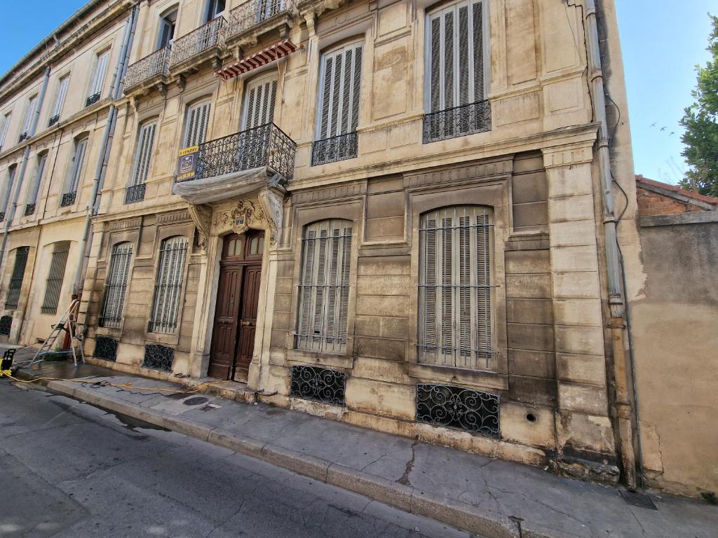 un vieux bâtiment avec des fenêtres et une porte dans une rue dans l'établissement Nimes: Appartement l'Auguste Centre-Ville., à Nîmes