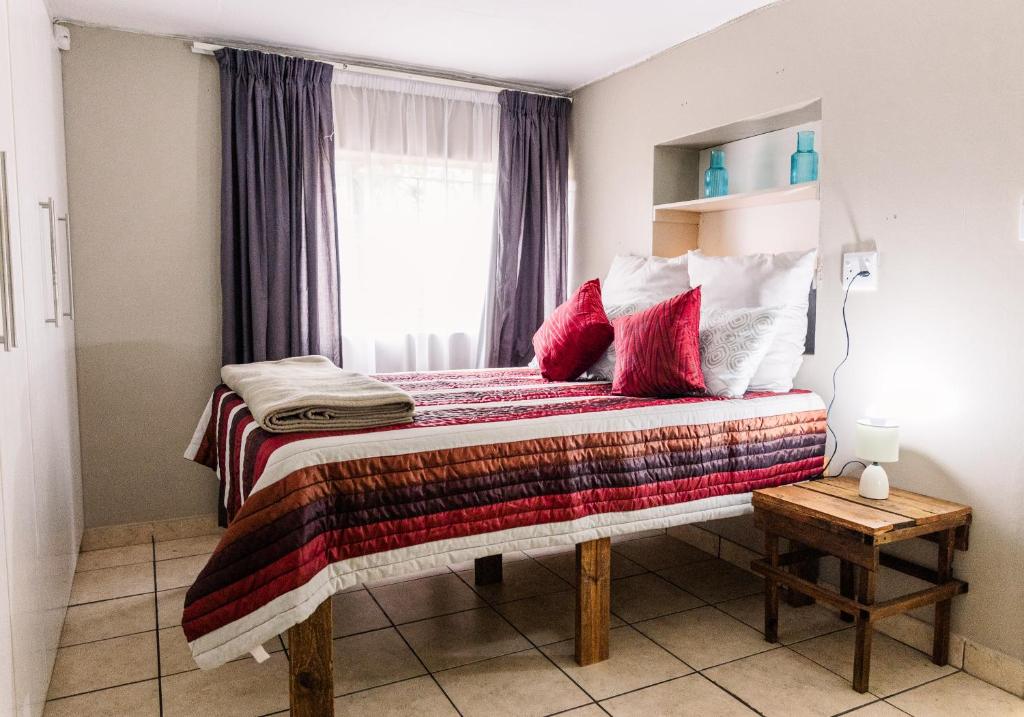 a bedroom with a bed with red pillows and a window at Stamvrug 9 B in Nelspruit